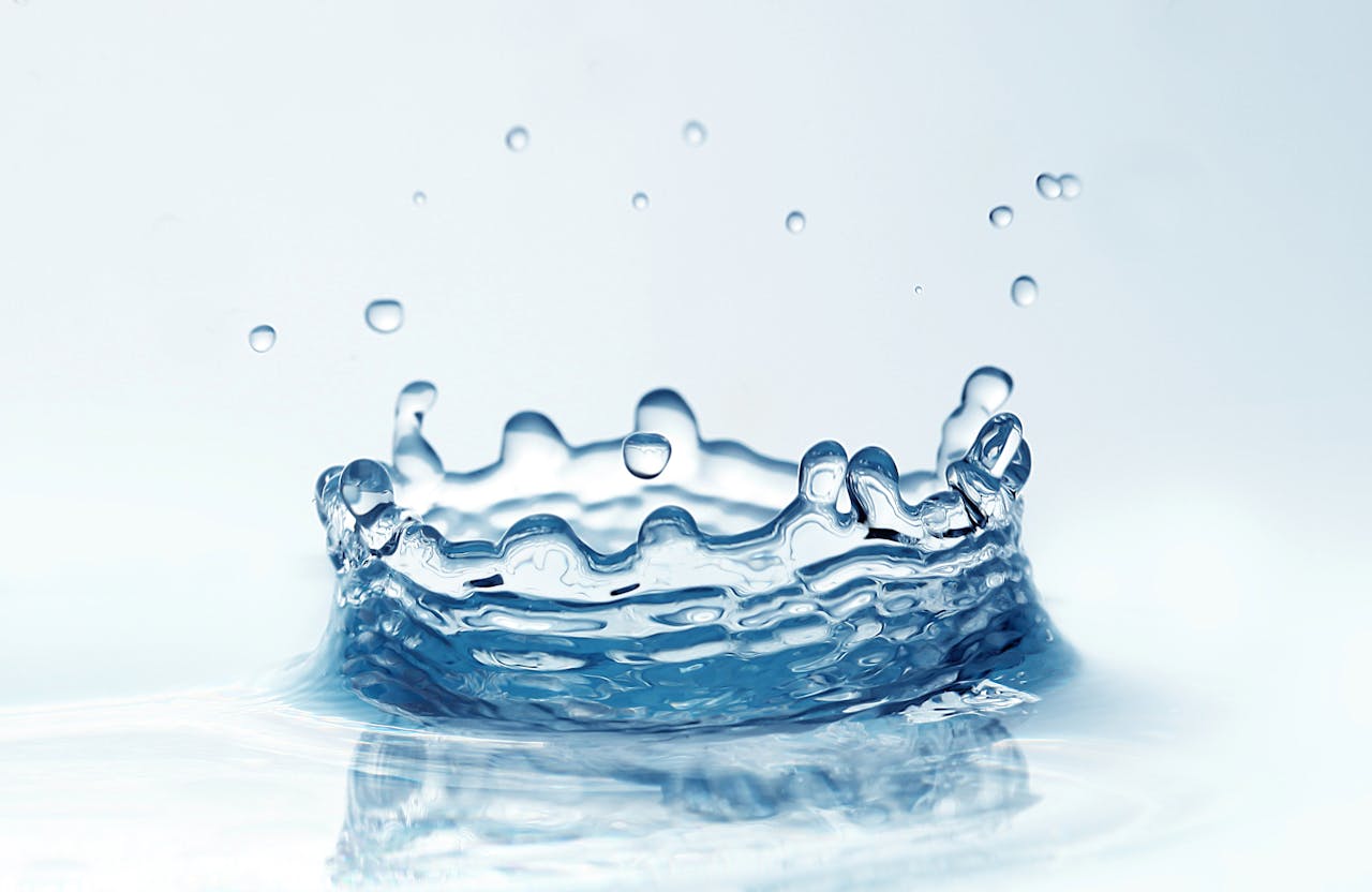 Dynamic close-up of a water droplet splash on a white background, showcasing clarity and motion.